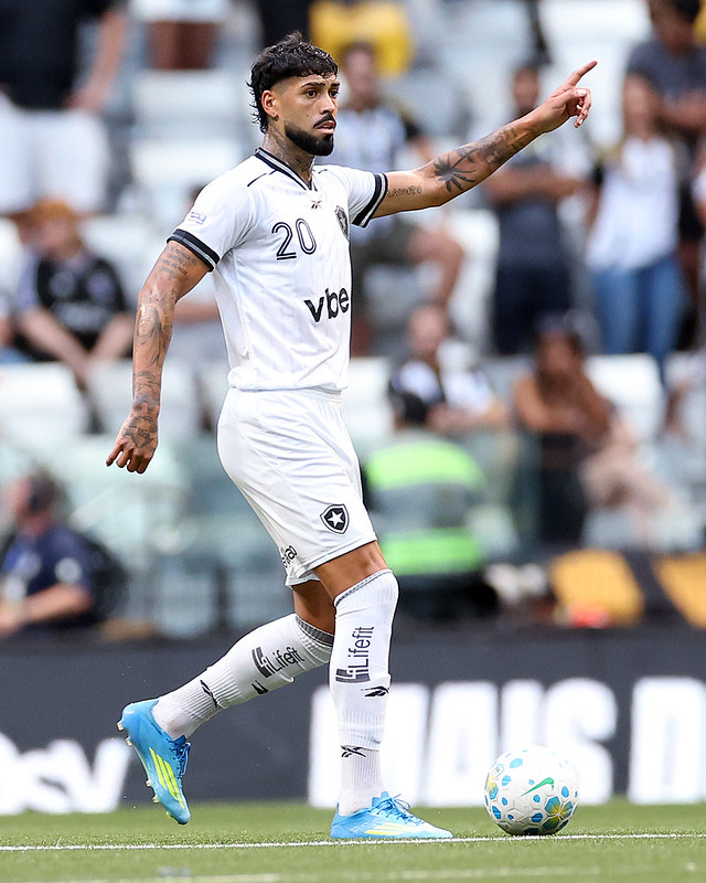 Alexander Barboza em campo pelo Botafogo, apontando durante partida.