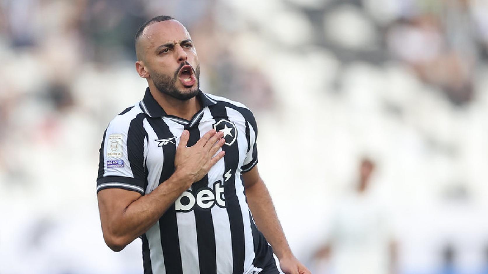 Arthur Cabral comemora gol pelo Botafogo com a mão no escudo da camisa.